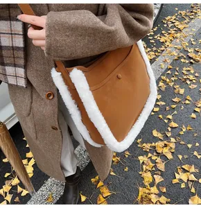 Detail of suede bucket bag with white fleece trim worn by model on autumn leaves