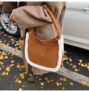 Detail of brown faux suede bucket bag with white faux fur trim and adjustable strap