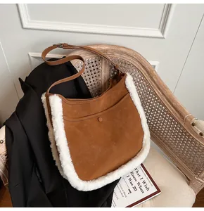 Detail view of brown suede hobo bag with white faux shearling trim on a wooden chair