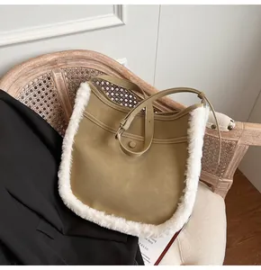 Detail of khaki suede bucket bag with soft white faux shearling trim on a wooden chair