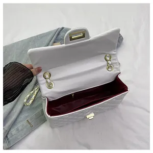 Detail view of white quilted handbag showing burgundy interior and internal zipper pocket