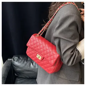 Detail of red quilted leather handbag with gold chain strap and metallic twist lock