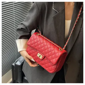 Close-up of red quilted leather handbag featuring a gold metal turn-lock and chain strap