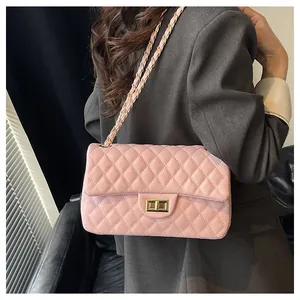 Detail of pink quilted leather shoulder bag with gold clasp and chain strap on shoulder