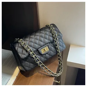 Close-up of black quilted leather handbag with gold turn-lock and chain strap
