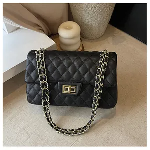 Close-up of black caviar leather texture and gold metal turn-lock on a flap handbag