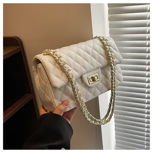 Detail of white quilted leather texture and gold metal twist lock on shoulder bag