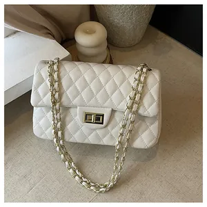 Detail view of white quilted faux leather bag with gold chain and metal twist lock