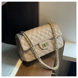 Detail of beige quilted shoulder bag with gold chain strap and turn-lock closure