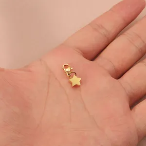 Minimalist gold star pendant with lobster clasp shown on palm for size reference