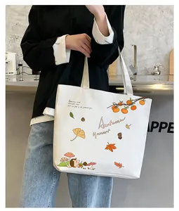 Detail of white canvas tote bag featuring autumn harvest illustrations and model lifestyle