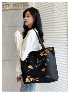 Detail of black canvas tote bag featuring autumn harvest hedgehog and leaf patterns
