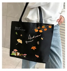 Detail view of black canvas tote bag featuring autumn hedgehog and leaf illustrations