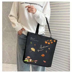 Detail of black canvas tote bag featuring autumn harvest print with hedgehog and maple leaves