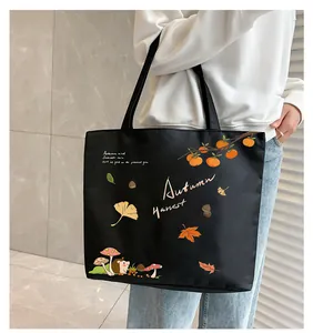 Detail of black canvas tote bag featuring autumn hedgehog and maple leaf illustrations