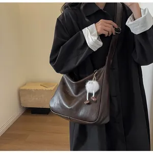 Detail of soft dark brown leather hobo bag with plush charm on a fashion model