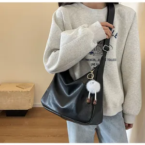Detail of black large capacity shoulder bag with soft PU leather and plush pendant