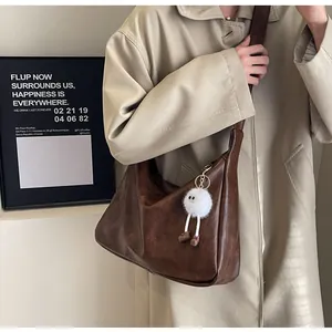 Detail of dark brown soft leather hobo bag with cute white plush monster pendant