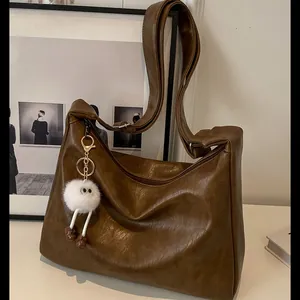 Minimalist large brown faux leather crossbody bag with a white plush charm detail