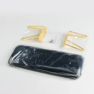 Unassembled components of a black leather nail arm rest with gold metal legs and screws