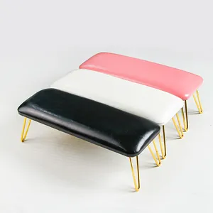 Detail of ergonomic leather manicure footrest stools in pink, white, and black with gold legs