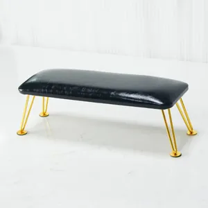 Close-up of black leather nail arm rest with gold metal legs and non-slip pads