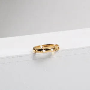 Detail of 18k gold plated hollow star ring resting on a white stone textured surface