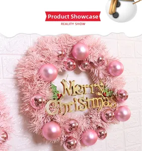 Detail of pink Christmas wreath with decorative baubles and a golden Merry Christmas sign