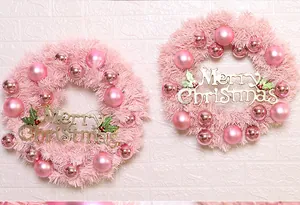 Macro view of pink Christmas wreath with matte baubles and golden Merry Christmas sign