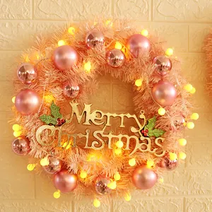 30cm Pink Christmas wreath with golden Merry Christmas sign and LED lights on a wall
