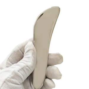 Macro shot of mirror-polished stainless steel Gua Sha tool edge with smooth metallic curves
