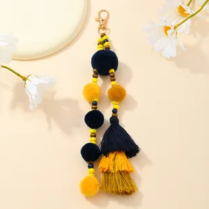Dettaglio del portachiavi con pompon, perle in legno e nappe per borse a mano
