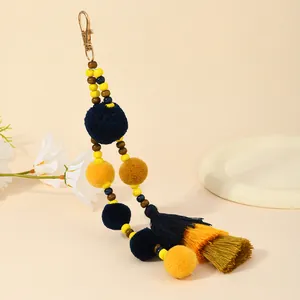 Dettaglio portachiavi bohémien con pompon di peluche, perline di legno e nappe colorate