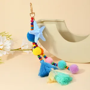Dettaglio di portachiavi boho colorato con stella marina, pompon e nappe su un vaso