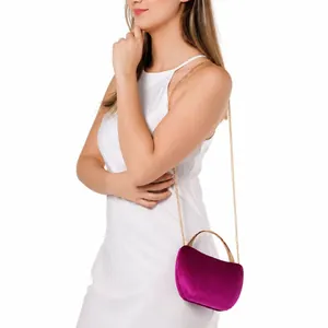 Detail of fuchsia snake-pattern evening bag with gold metal handle and chain strap