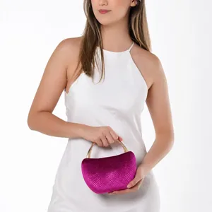 Detailed fuchsia snake texture evening bag with gold handle held by model in white dress