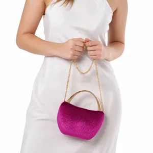 Close-up of a velvet purple evening bag with a gold handle on a white satin dress