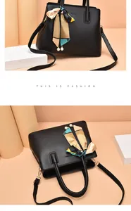 Detail of black leather handbag featuring gold embossed logo and decorative silk scarf