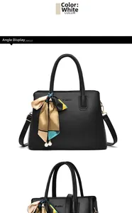 Detail of black textured tote bag featuring a silk scarf handle and pearl pendant