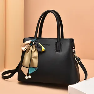 Elegant black faux leather handbag with decorative silk scarf and pearl pendant