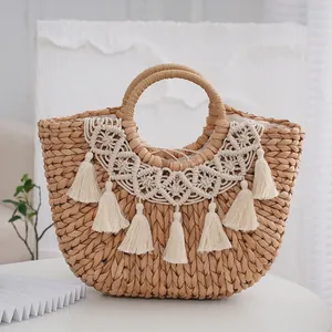 Detail of semi-circle straw tote bag with macramé tassels and woven round handles