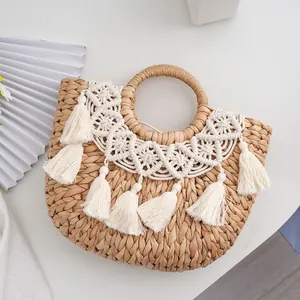 Detailed close-up of straw handbag featuring white cotton tassels and woven textures