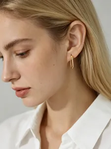 Close-up of elegant gold beaded U-shaped hoop earrings worn by a model in profile
