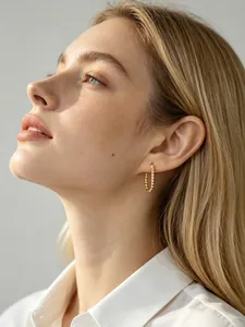 Close-up of gold beaded U-shaped hoop earrings in s925 silver worn by a female model