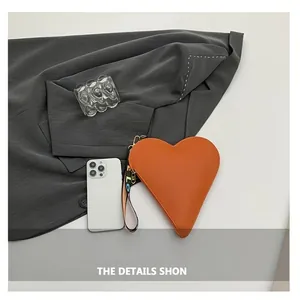 Macro shot of orange heart-shaped leather handbag with LOVE letter wristlet strap