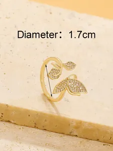 Close-up of golden butterfly open ring with zircon stones on stone background