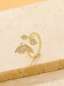 Close-up of golden butterfly open ring with sparkling zircon stones on stone base