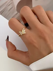 Detailed close-up of a golden butterfly ring with sparkling crystals on a woman's finger