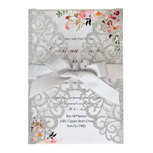 Elegant laser-cut silver glitter wedding invitation with gray ribbon bow and floral insert