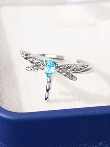 Detailed view of silver dragonfly ring featuring a pear-cut blue gemstone on velvet box